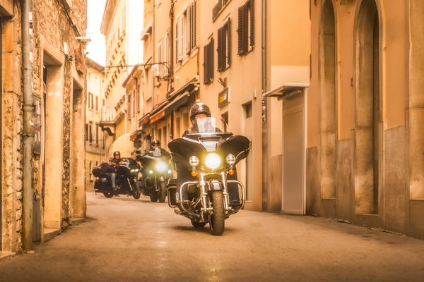 Harley-Davidson motorcycles riding down a narrow street