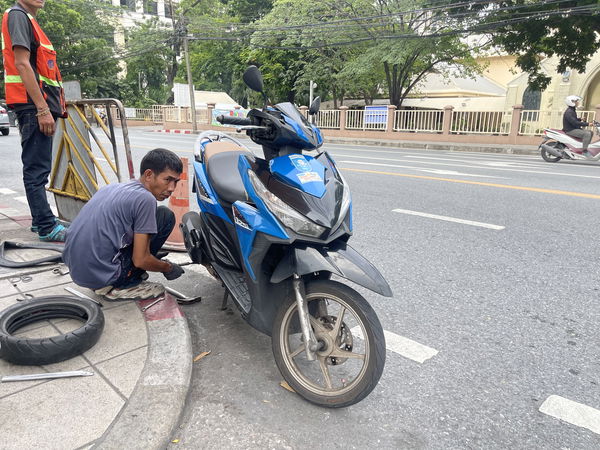 A man repairing a scooter at the side of the road