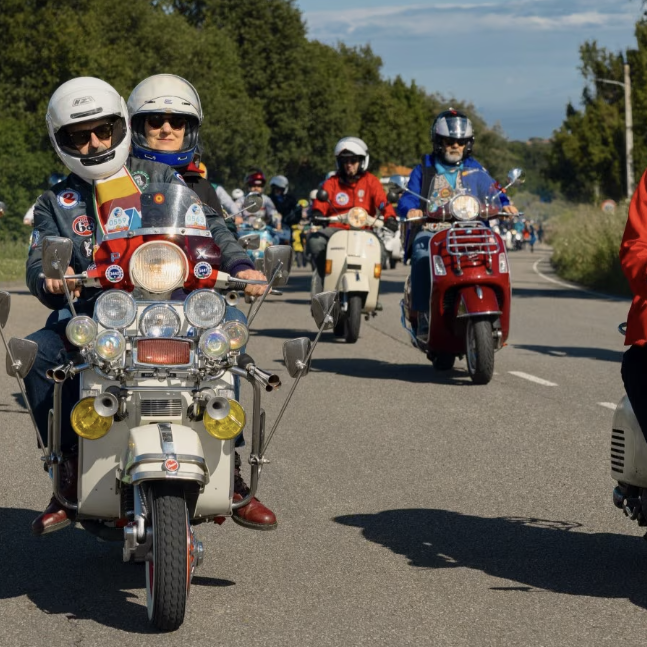 Vespa scooters on the road at World Days event. Credit - Vespa