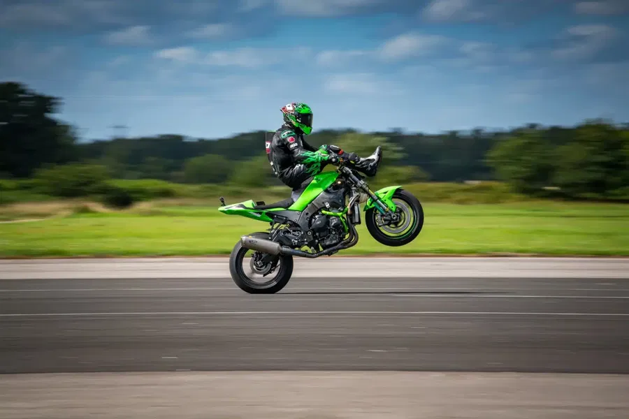 JD Stunts pulling a wheelie while seated on the handlebars