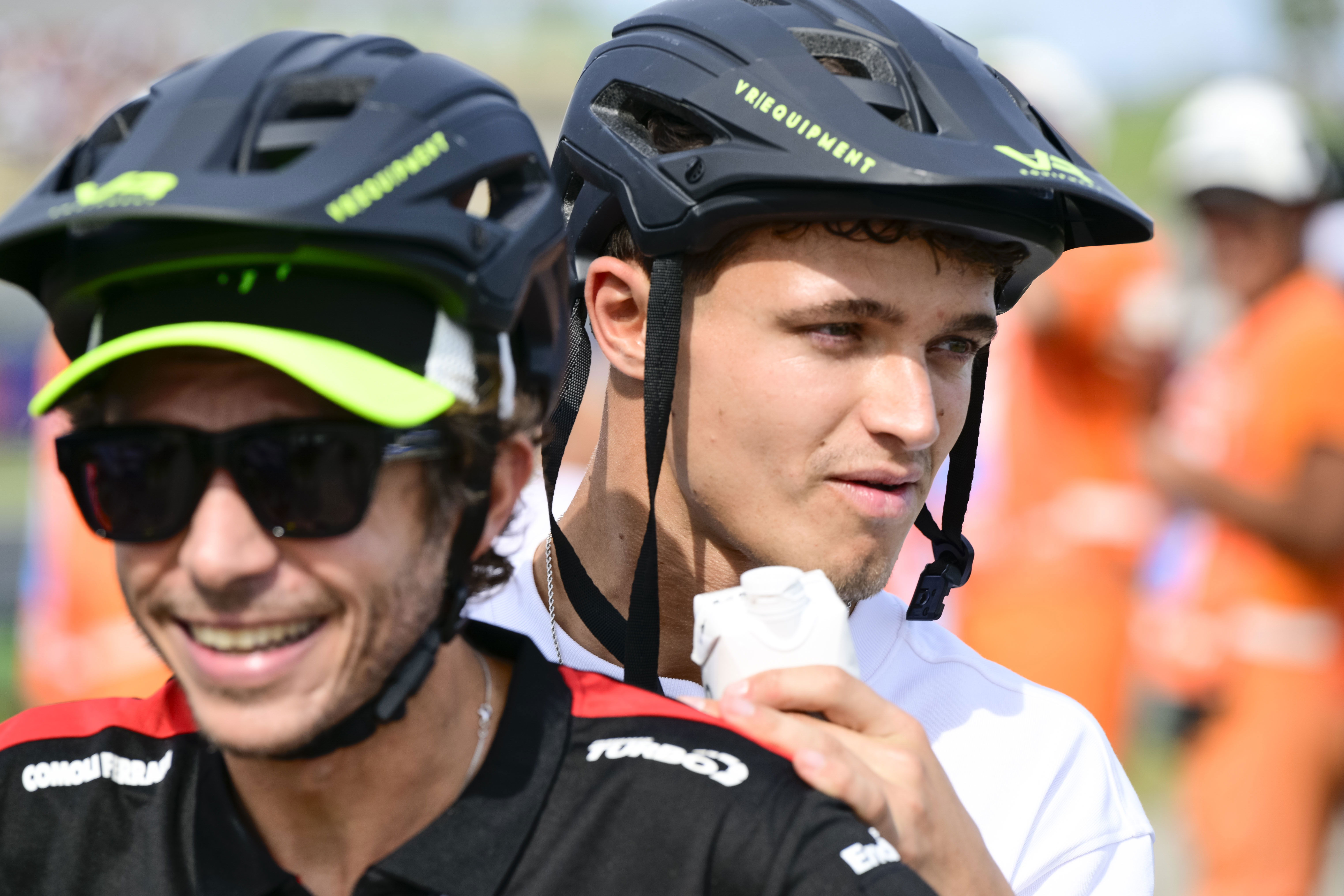 Lando Norris on the back of a scooter ridden by Valentino Rossi