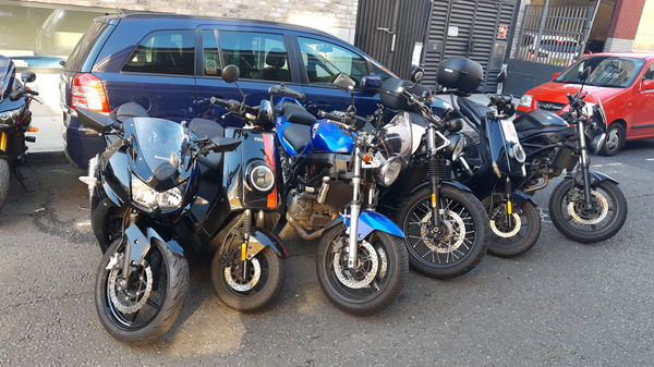 Six motorcycles parked alongside a car taking up the same space.