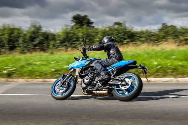 A Suzuki motorcycle being ridden along a country lane