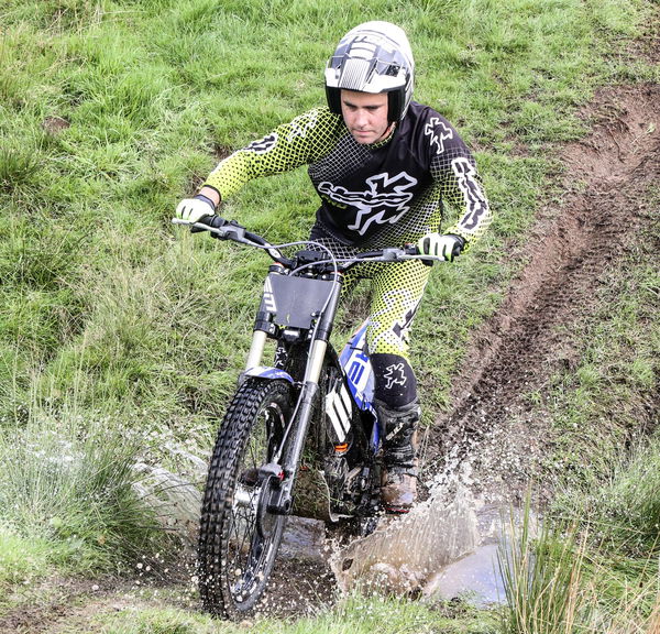 A trials bike crosses a stream