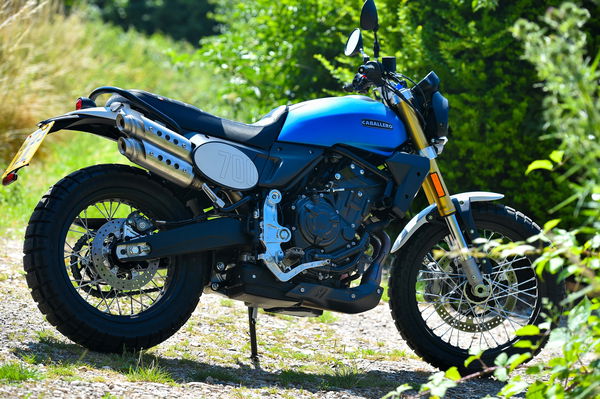 A Fantic motorcycle parked in front of foliage 