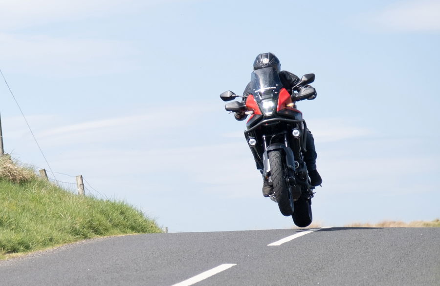 A motorcycle cresting a rise in the road