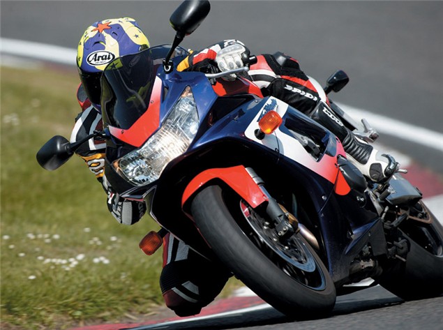 A red, white and black 2000 Fireblade CBR900RR being ridden around a racetrack