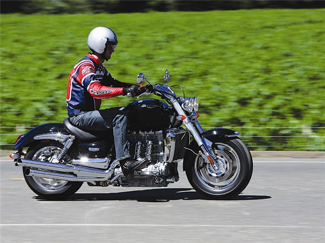 A red and black 2004 Triumph Rocket 3 being ridden on a country road