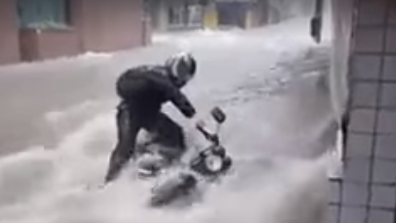 WATCH: Biker and bike washed down a flooded road