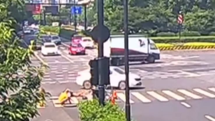Watch: Car crash sends motorcyclist sliding down open manhole