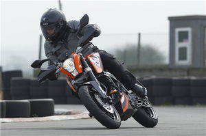 A black and orange 2011 KTM 125 Duke being ridden around a track