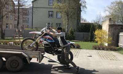 Man loading bike onto trailer using ironing board