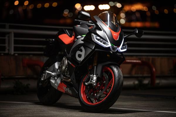 Aprilia RS660 parked up at night with the headlights on