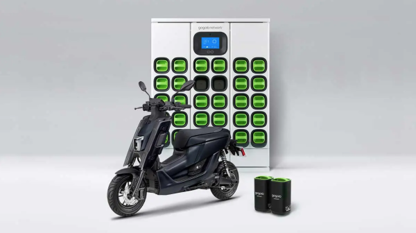 A Yamaha electric scooter in front of a charging bank of batteries