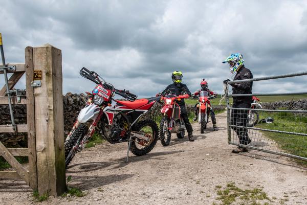 Three trail bike riders navigating a gate