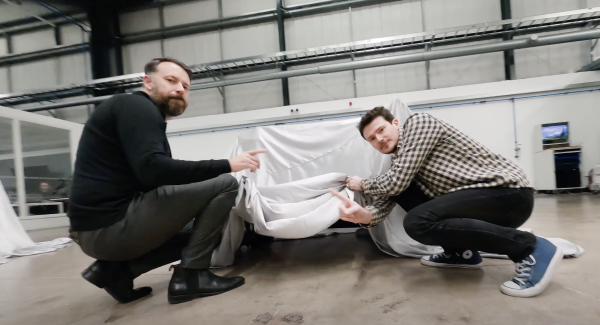 Two men lifting a sheet off a new Norton Motorcycle