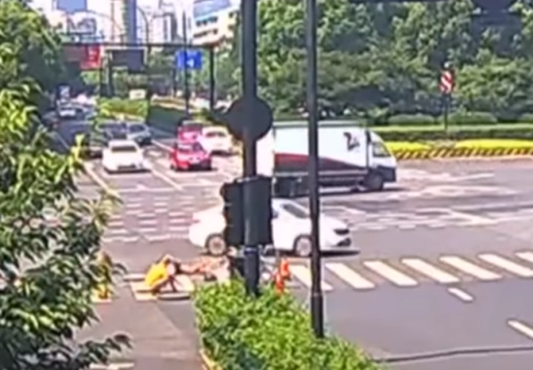 Watch: Car crash sends motorcyclist sliding down open manhole