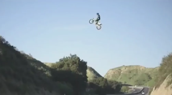 Crazy rider jumps dirt bike over motorway