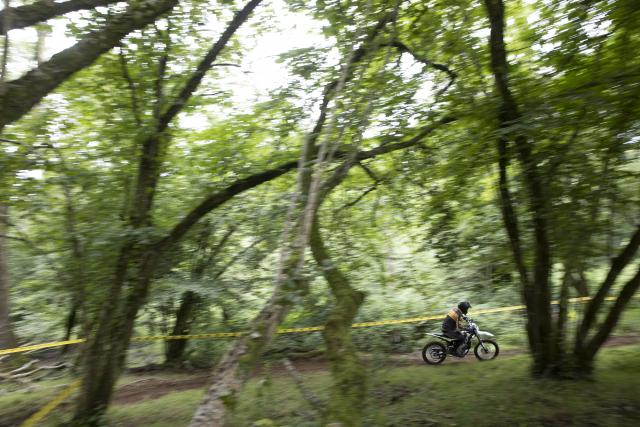 a dirt bike being ridden through a forest 