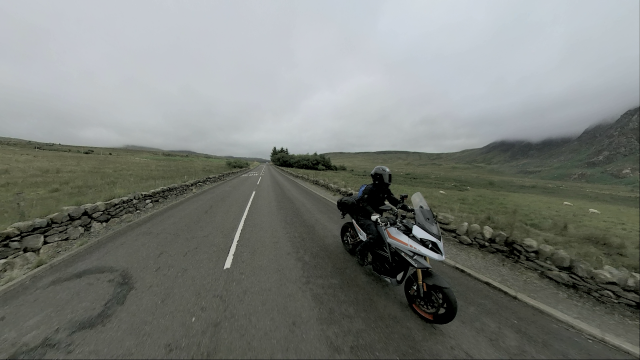 an electric motorcycle riding along a Welsh road