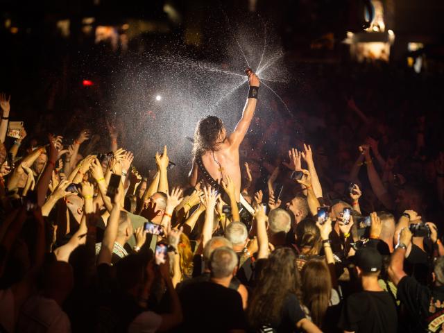 A singer in a rock band crowd surfs during a concert