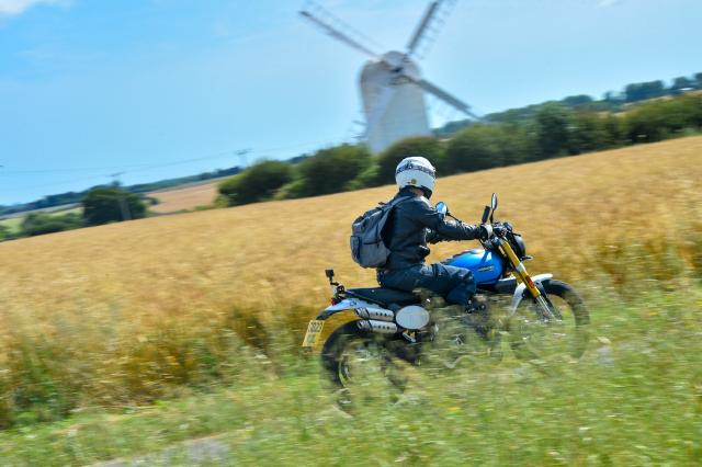 A motorcyclist passes in front of a windmill