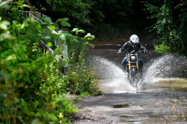 A motorcycle rider fords a stream
