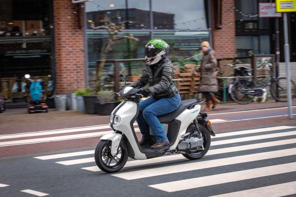 Yamaha NEO&#039;s riding through an urban area. Ride wearing blue riding jeans and black, leather riding jacket and Joker Ruroc ATLAS 4.0 helmet.