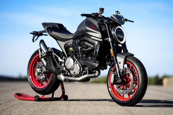 A red and black 2021 Ducati Monster parked on a racetrack
