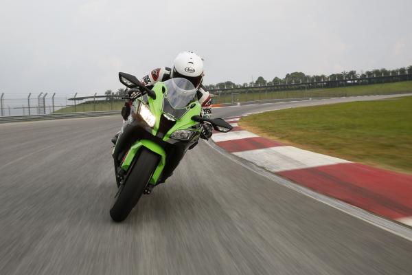 A front-on picture of a green and black 2016 Kawasaki ZX-10R being ridden on a track
