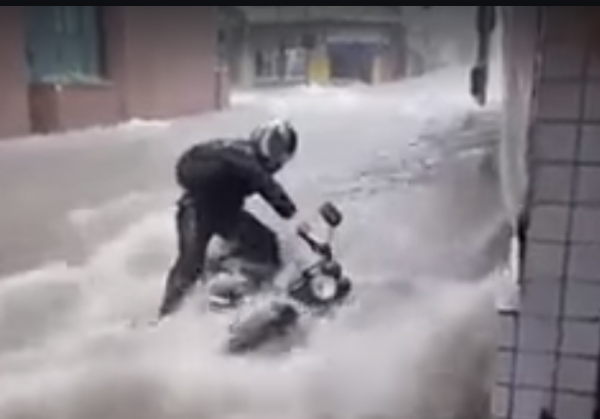 WATCH: Biker and bike washed down a flooded road