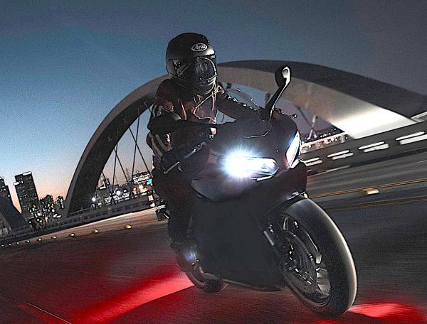 A motorcycle riding along a road at night