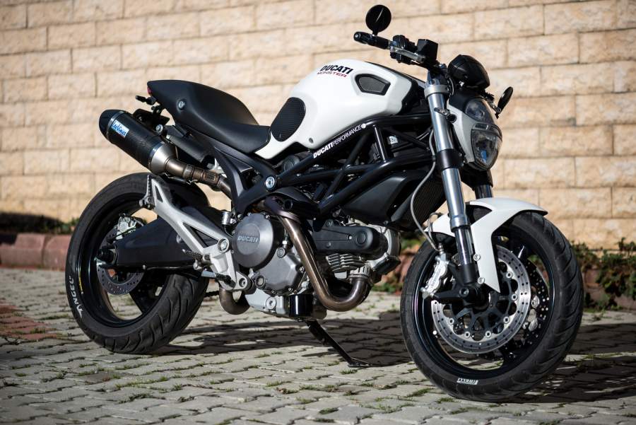 A black and white Ducati Monster 696 parked on a cobbled road