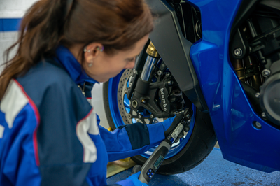 Mechanic servicing Suzuki motorcycle. - Suzuki